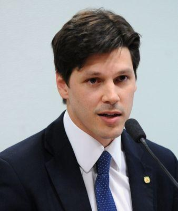 Ein Mann in Anzug und Krawatte spricht in ein Mikrofon an einem Rednerpult, wahrscheinlich um die Genehmigung eines Gesetzes durch die Regierung zu kommentieren.