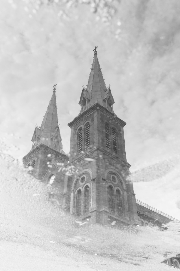 Ein Gebäude mit Wolken oben und Nebel im Vordergrund, gespiegelt auf einem Spiegel.