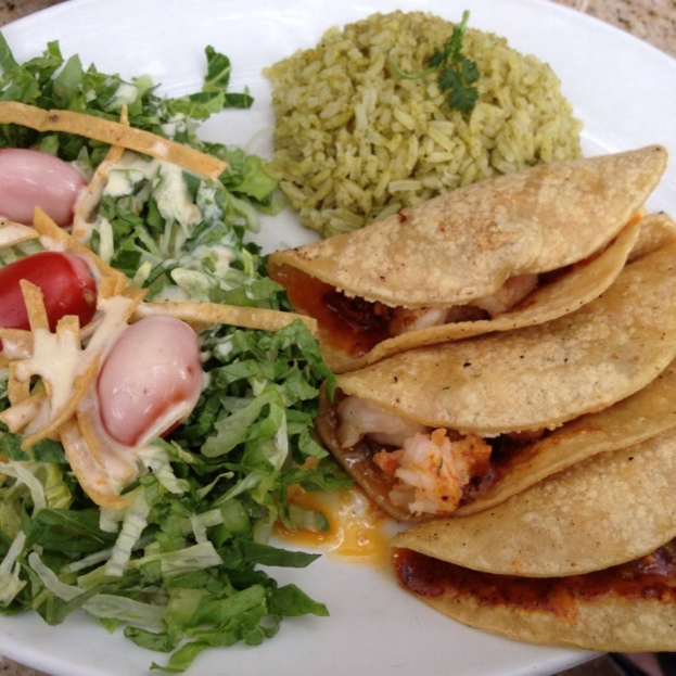 Ein weißer Teller mit einer Portion Reis, Gemüse und Snacks, die darauf angerichtet sind.