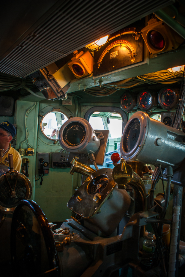 Das Innere eines Zuges mit Sitzen und verschiedenen Gegenständen; eine Person in einem gelben T-Shirt steht auf der linken Seite des Bildes.