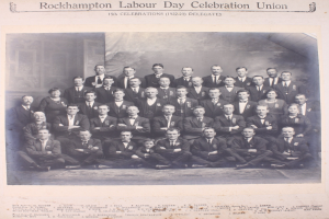 Gruppe von Menschen in Blazern und Krawatten, die für ein Foto posieren mit "Rockhampton Labour Day Celebration Union"-Text oben und unten.