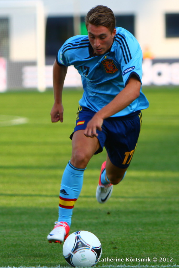 Ein Mann in einem blauen T-Shirt, der Fußball auf einem Feld spielt.