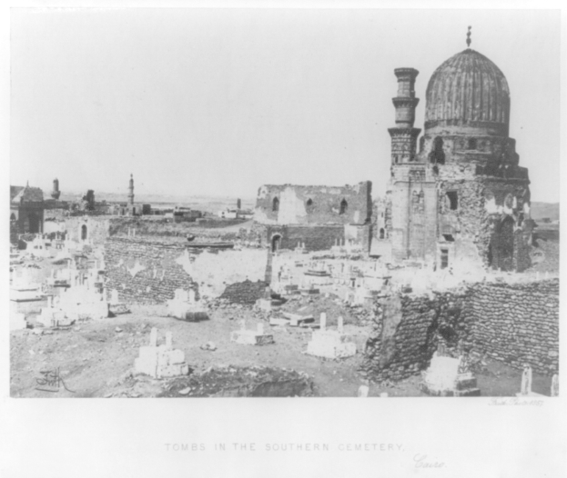 A black and white photo of a cemetery with tombstones, a mosque in the background, and text at the bottom.
