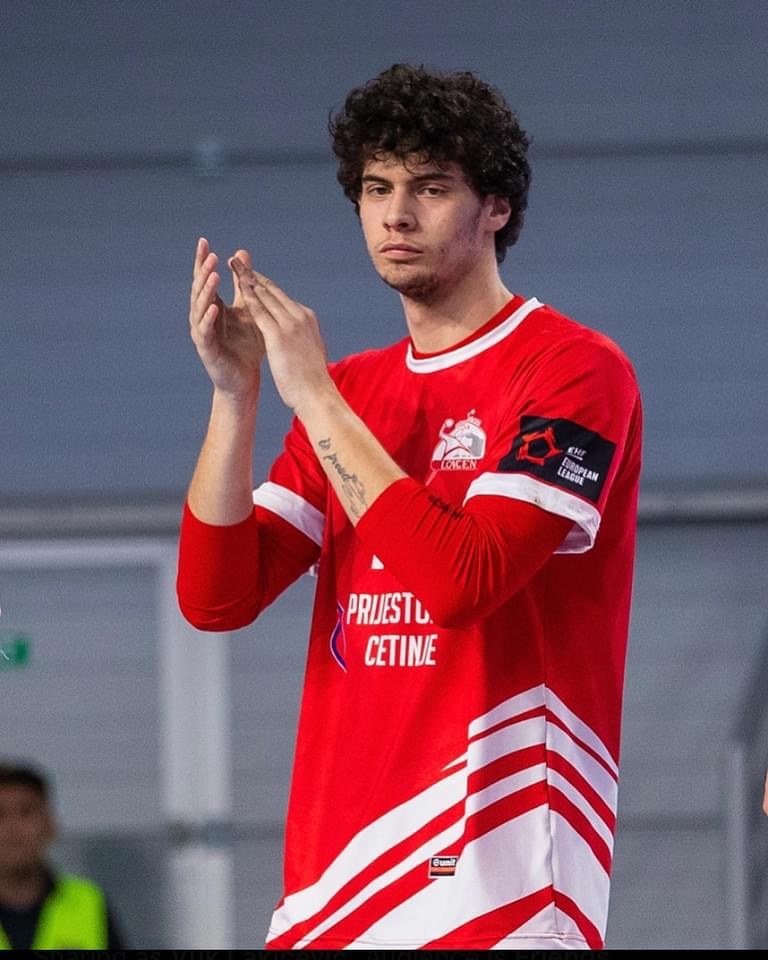Ein Mann in einem roten und weißen Hemd klatscht in der Vordergrund, mit einer anderen Person und einer Wand im Hintergrund, Text unten lautet 'Kopenhagen Futsal Club - Foto 1'.