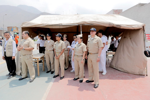 Polizistinnen und Polizisten vor einem Zelt mit Bergen im Hintergrund.