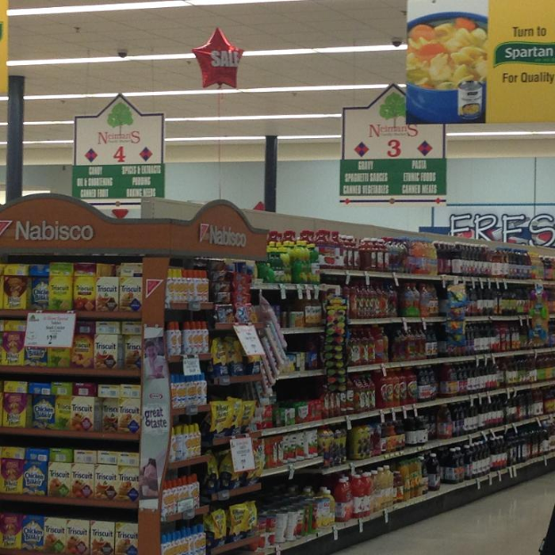 Ein Supermarkt-Innere mit sichtbaren Lebensmitteln, Deckenlampen und Schildern.