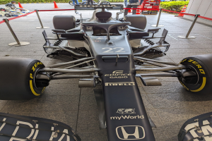 Ein McLaren Mercedes MP4-23 Formel-Eins-Auto bei der Singapore Grand Prix, umgeben von Barrieren, Verkehrskegeln, Menschen, Fahrzeugen, Pflanzen, Bäumen und einem Gebäude im Hintergrund.
