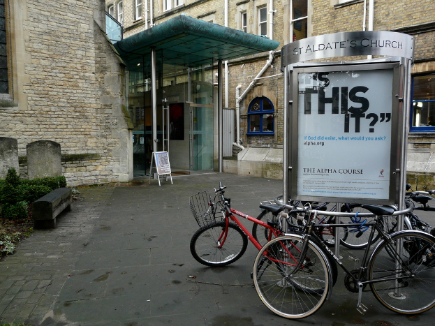 Gebäude mit Fahrrädern und Brettern davor, Sträucher auf der linken Seite.