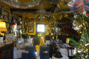 Ein Raum mit Stühlen, Tischen, Dekorationsgegenständen und Fotografien an der Wand.