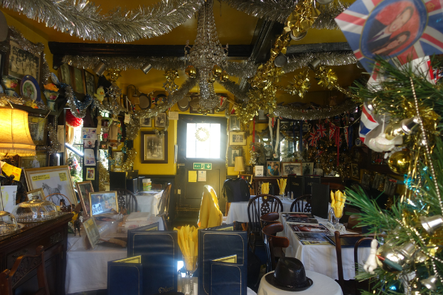 Ein Raum mit Stühlen, Tischen, Dekorationsgegenständen und Fotografien an der Wand.