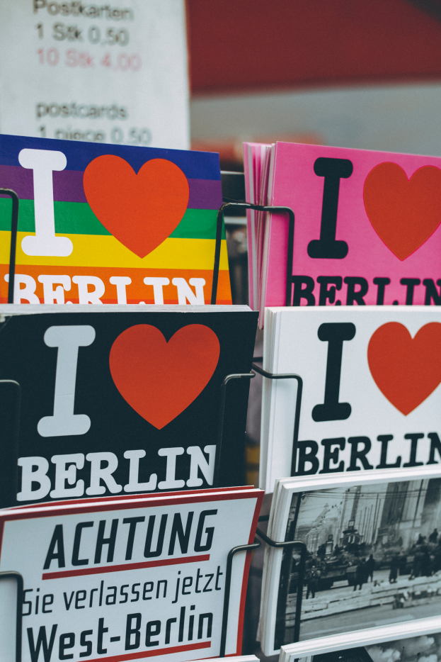 Ein Regal mit verschiedenen Büchern und Postern mit der Aufschrift "Ich liebe Berlin" vor einem unscharfen, verträumten Hintergrund.