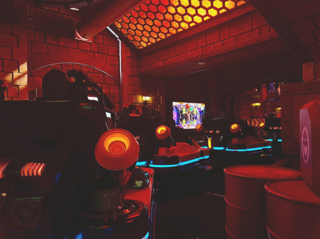 Ein hell erleuchteter Raum voller verschiedener Arcade-Videospielautomaten, Bildschirme und andere Geräte, die eine energiegeladene Atmosphäre schaffen.