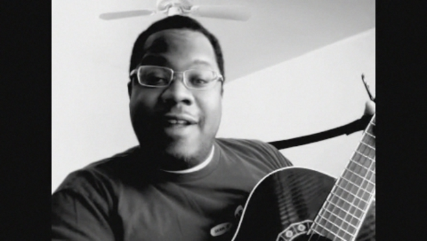 Ein Mann mit Brille spielt Gitarre, mit einem Ventilator darüber.