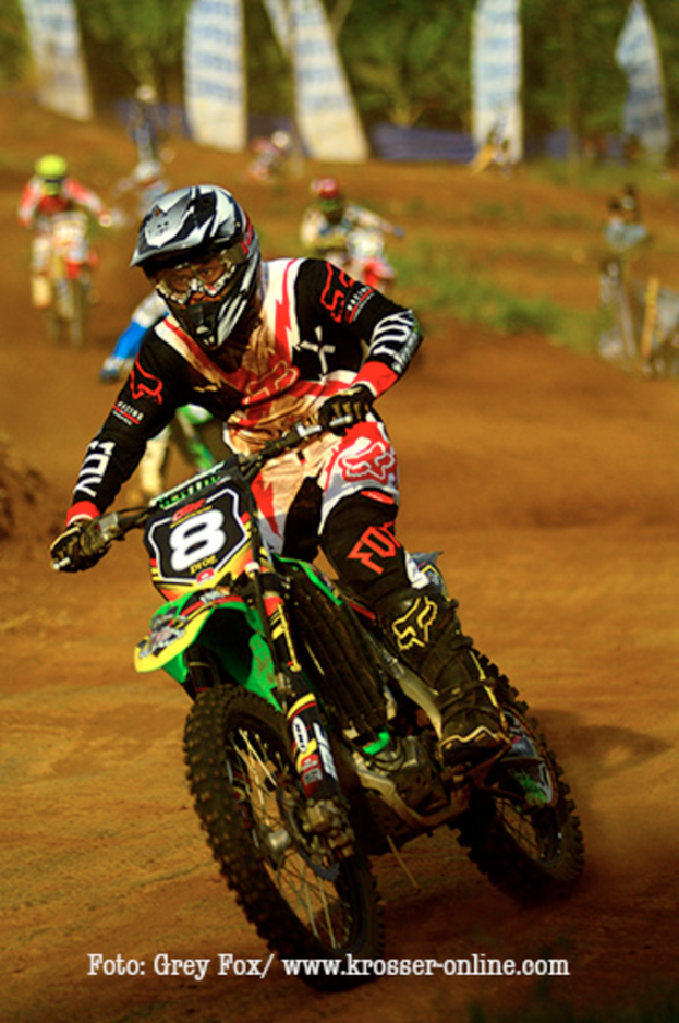 Mehrere Motorradfahrer mit Helmen rennen, mit Text unten im Bild.