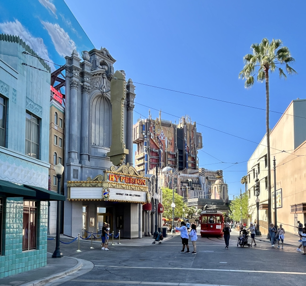 Lebendige StraßenSzene in Universal Studios Hollywood mit Passanten, einem Fahrzeug und umliegenden städtischen Elementen unter einem sichtbaren Himmel.