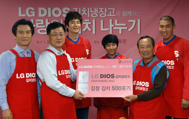 Eine Gruppe von Männern hält eine große LG-Firmenkarte mit einem Banner im Hintergrund.