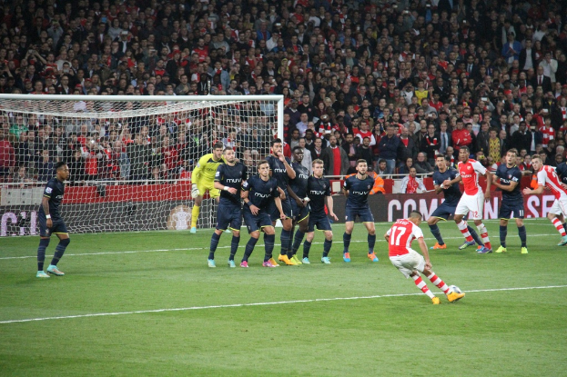 Ein Mann in einem blauen T-Shirt spielt Fußball auf einem Feld.