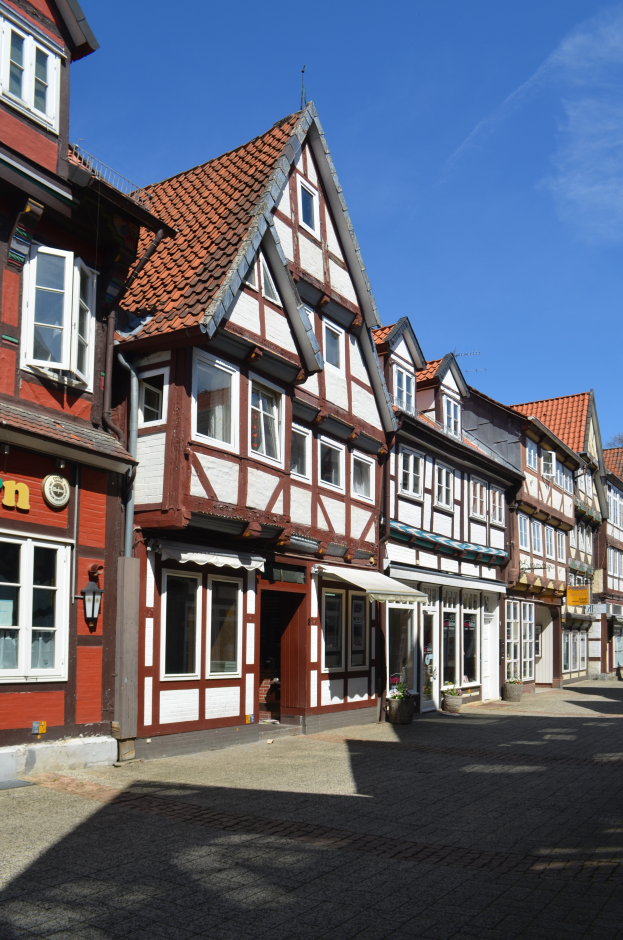Ein Kopfsteinpflasterweg in der Altstadt von Heidelberg mit Gebäuden im Vordergrund, einem klaren blauen Himmel im Hintergrund und einer Laterne, die die Straße auf der linken Seite beleuchtet.