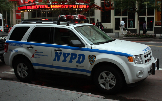 Ein weißes Auto steht am Straßenrand mit Läden im Hintergrund, die Glasdoors aufweisen.