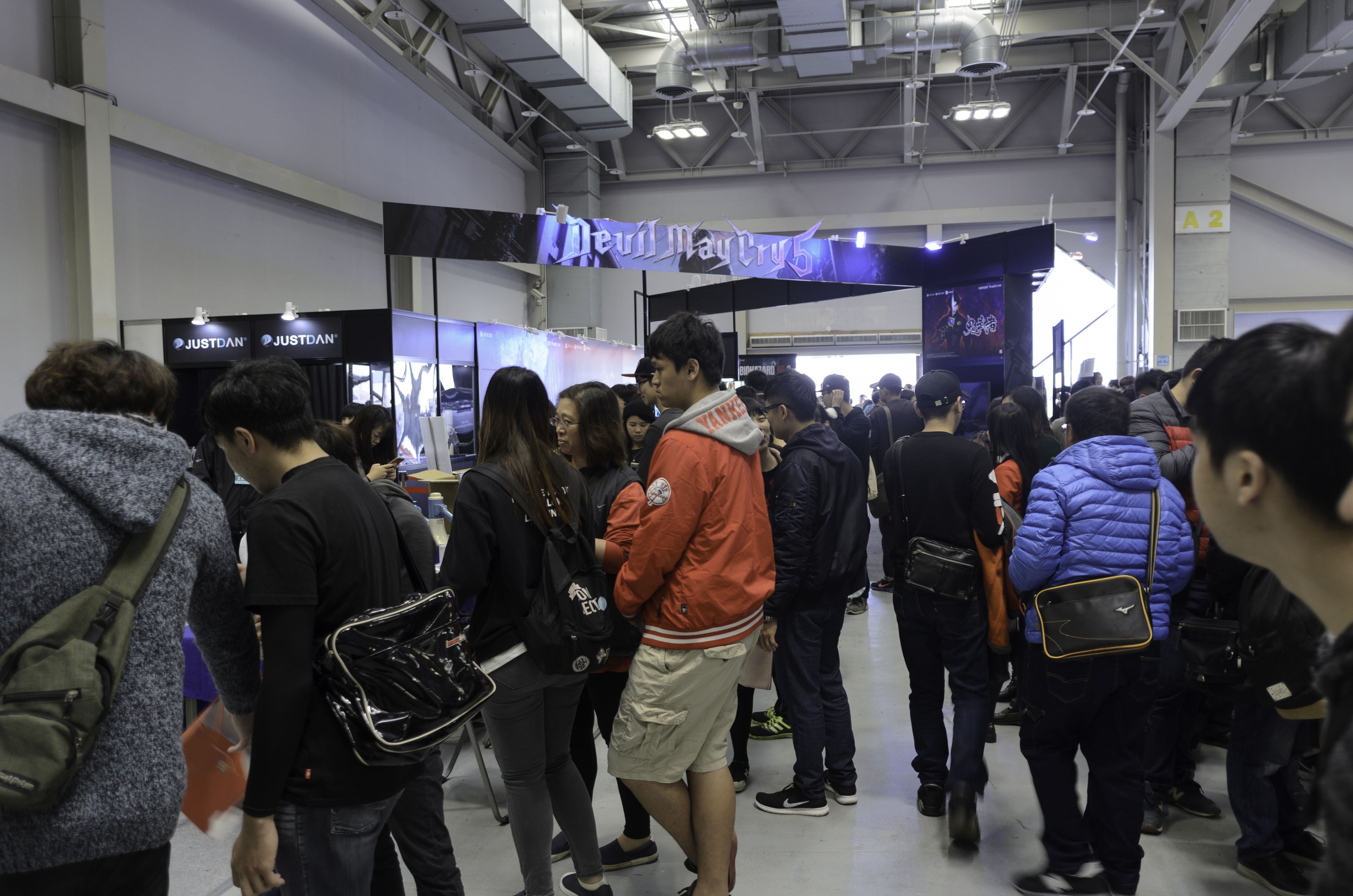 Menschen vor einer Menschenmenge an einer Gaming-Messe, mit Brettern, Lichtern und Rohren im Hintergrund.