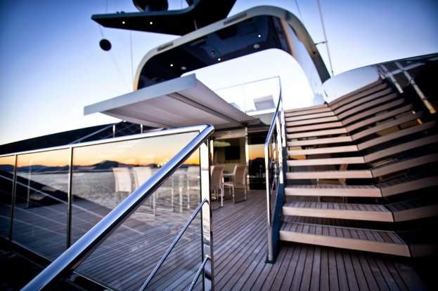 Ein modernes Glashaus mit Treppen auf der rechten Seite, Stühle um einen Tisch auf der linken Seite und ein Glasgeländer links unten.