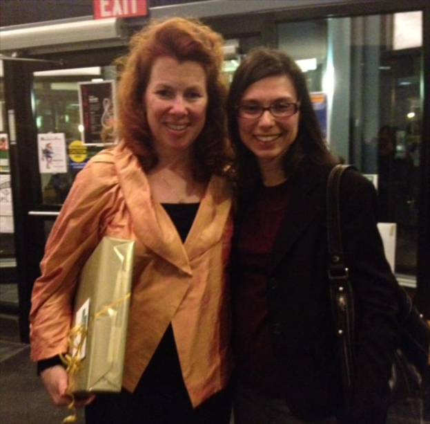 Zwei Frauen, die vor einem Geschäft mit einem roten EXIT-Schild im Hintergrund stehen und lächeln.