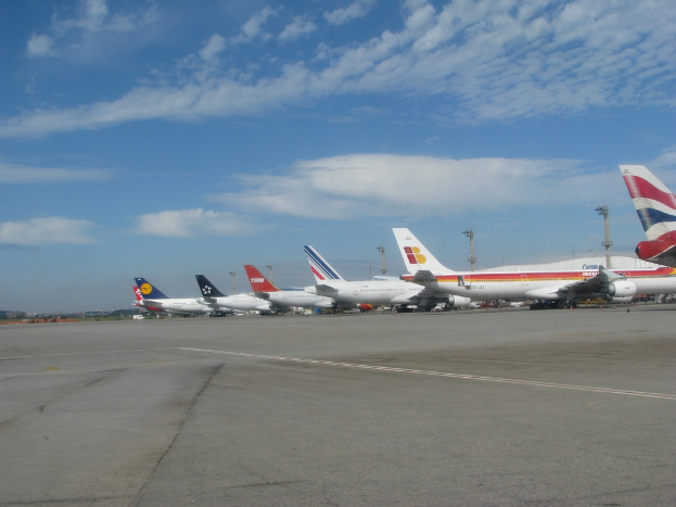 Eine Start- und Landebahn mit einigen Flugzeugen, Masten, Kabeln und einer bewölkten Himmel.