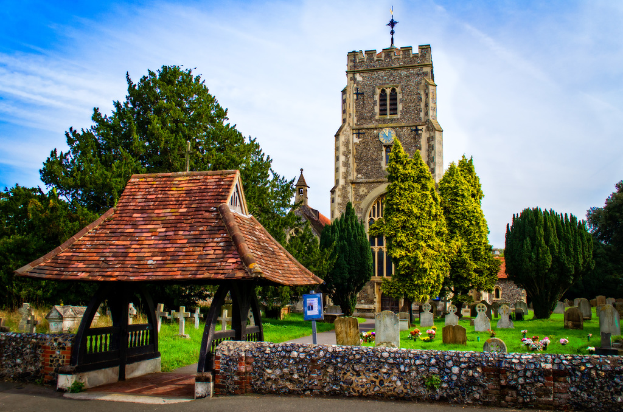 Ein bearbeitetes Bild mit Gebäuden, Bäumen, einer Wand, Friedhöfen, Gras und Blumen, mit einem Weg am Boden und Himmel oben.