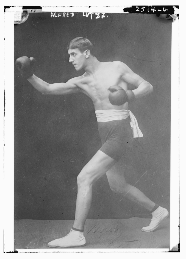 Ein Schwarz-Weiß-Foto eines Mannes in Boxhandschuhen und Shorts mit entschlossener Miene und Text oben und unten auf dem Bild.