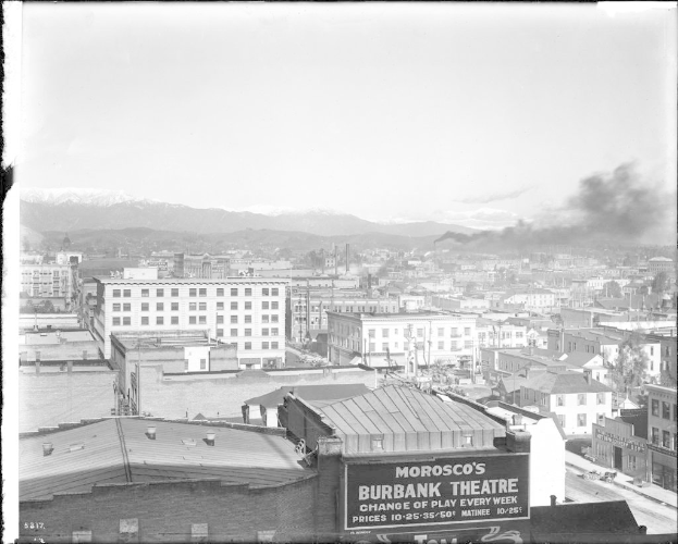 Ein Schwarz-Weiß-Bild von Gebäuden mit einer Fabrik, die Rauch ausstößt.