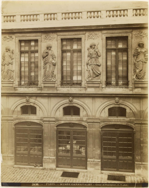 Altes Gebaude mit skulptierter Fassade, Fenstern, Tueren und Text unten.