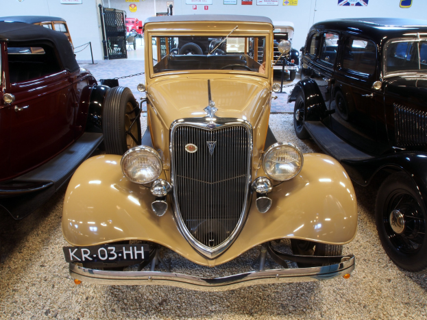 Eine Sammlung von Oldtimern auf einem Museumsboden mit Postern an der Hintergrundwand.