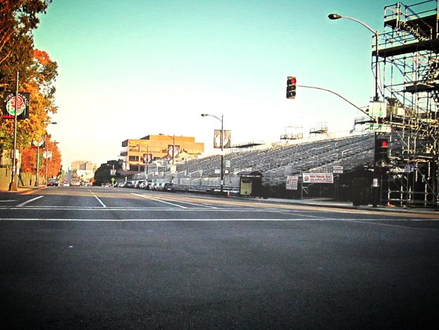 Eine Straße mit einer Ampel und Equipment auf der rechten Seite, Warnschilder und mehrere Fahrzeuge vor zahlreichen Bäumen auf der linken Seite.