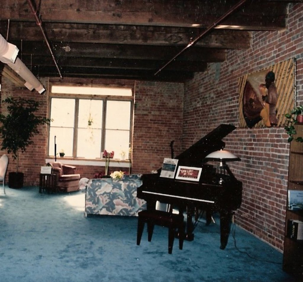 Ein Klavier mit zwei Notizbüchern darauf, eine Glasmalerei und ein Fenster im Hintergrund, unter einem schön gestalteten Dach.