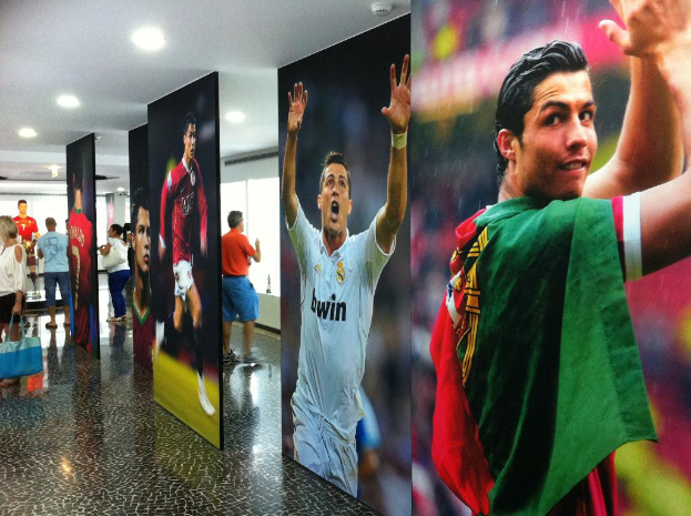 Ein Banner mit dem Fußballspieler Rolando, umgeben von Menschen auf der linken Seite und Lichtern oben.