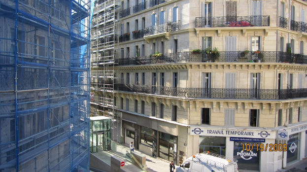 Ein großes Gebäude unter Bau auf der linken Seite, mit einem Geschäft auf der unteren rechten Seite.