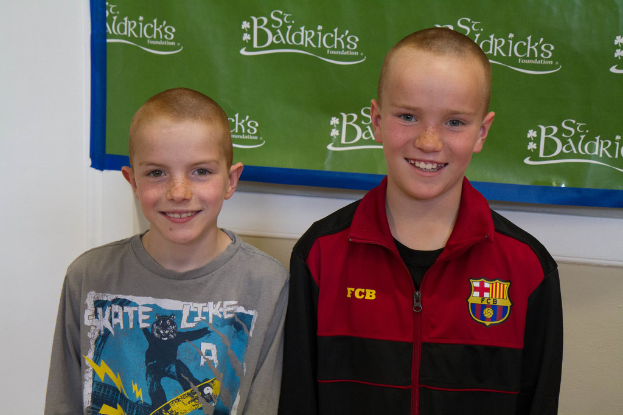 Zwei Jungen stehen zusammen, lächeln und haben ein Banner mit Text im Hintergrund.