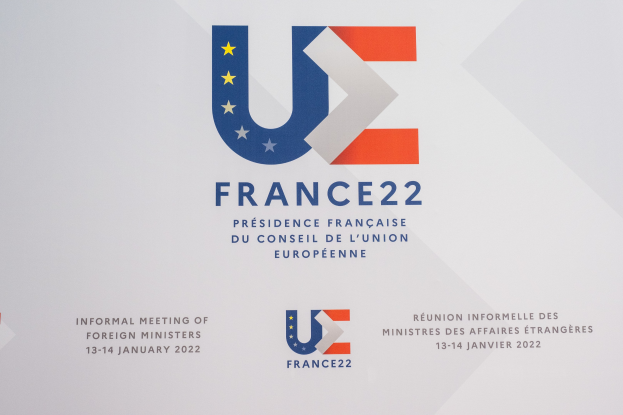 Plakat für die "Frankreich 22 - Informelle Zusammenkunft der Außenminister" mit dem Logo der Europäischen Union, das einen blauen Kreis, einen weißen Rahmen, einen weißen Stern und schwarzen zentrierten Text zeigt.