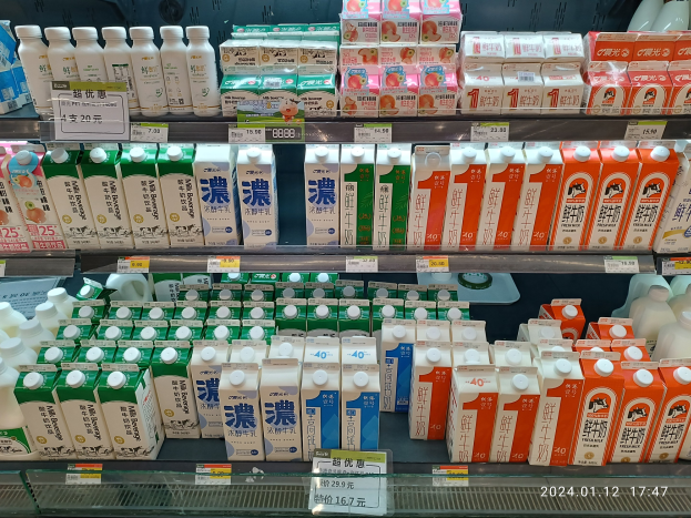 Eine Auslage in Japan gefüllt mit verschiedenen Milcharten in Flaschen, Schachteln und anderen Behältern, jeweils mit Preisschildern.