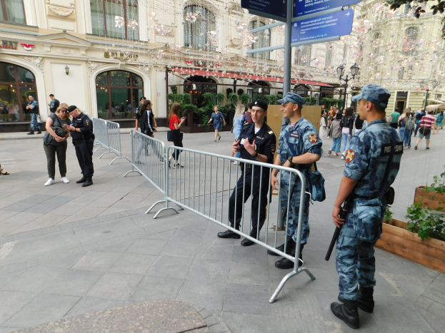 Polizeibeamte in Uniform stehen hinter Absperrungen einer Menge gegenüber, einige tragen Mützen und halten Waffen, mit Schildern und Gebäuden im Hintergrund während eines Anti-Terror-Einsatzes in Wien, Österreich.