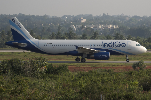 Indigo Airlines Airbus A320-200 auf dem Mumbai Airport-Flughafen mit Grünfläche, Bäumen, Gebäuden und klarem blauen Himmel.