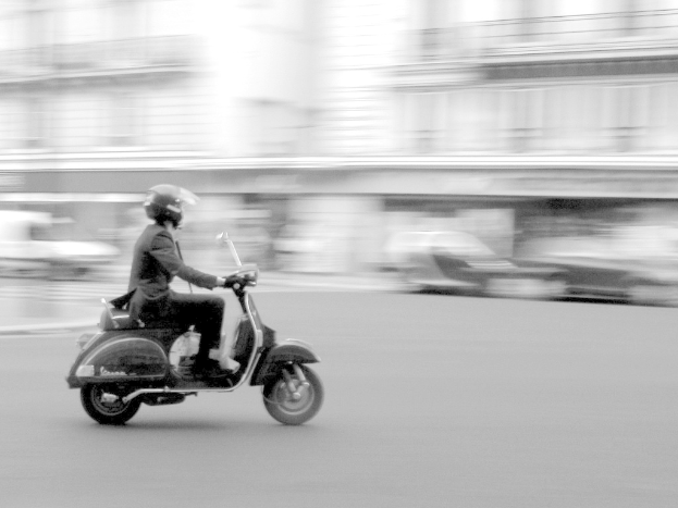 Eine Person, die ein Scooter auf einer Stra√e f√§hrt.