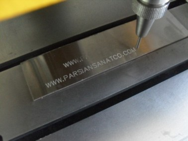 CNC-Fräsmaschine schneidet ein Metallobjekt mit eingraviertem Text während des Betriebs.