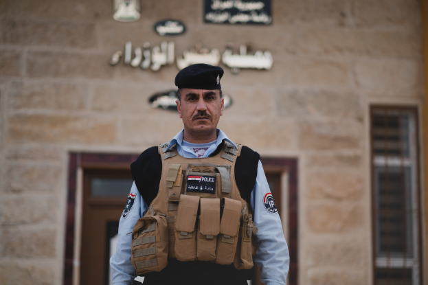 Polizist in Uniform vor einem Gebäude mit Türen, Fenstern und Wandtext