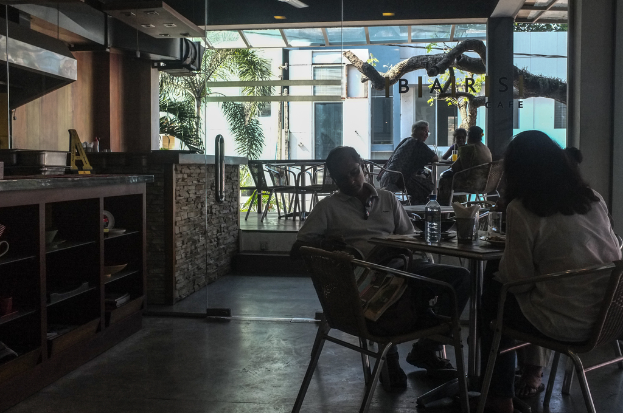 Ein Speisesaal mit Gruppen von Menschen an Tischen mit Flaschen und Gläsern und einem Schreibtisch im Hintergrund.