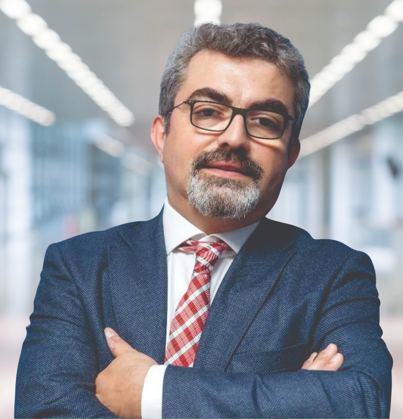 Ein Mann im Anzug und mit Krawatte, der die Arme verschränkt und eine Brille trägt, vor einem unscharfen Hintergrund steht, mit Text, der ihn als neu ernannten Marketingchef identifiziert.