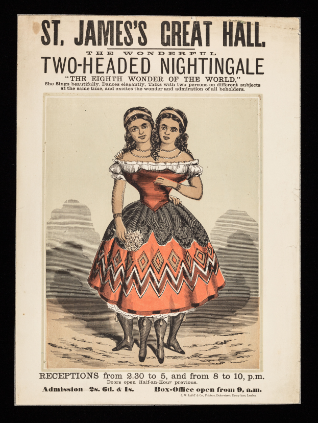 Zwei Frauen in Kostümen stehen lachend vor einem Plakat, das eine Veranstaltung mit einem zweiköpfigen Nachtigall im St. James's Great Hall ankündigt.