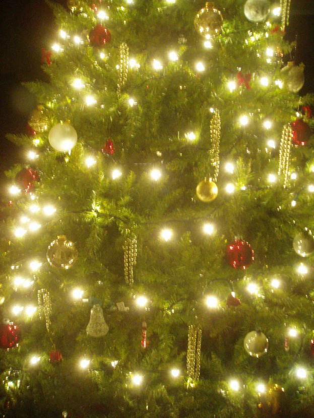 Ein Weihnachtsbaum mit Lichtern, Kugeln und verschiedenen Verzierungen.