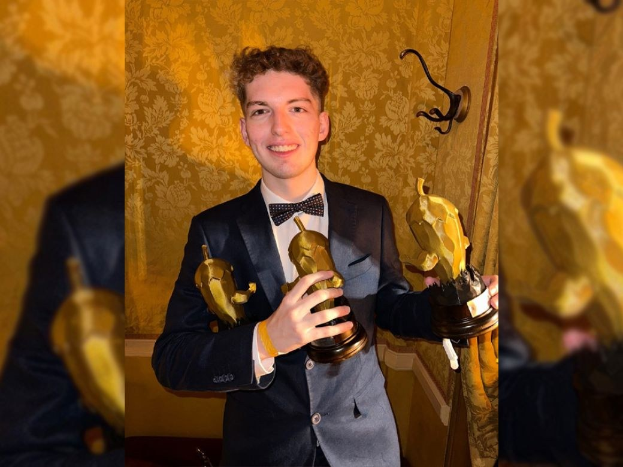 Ein Mann im Smoking hält eine Oscar-Statue, lächelt gegen eine Wand, nachdem er den Oscar für den besten Nebendarsteller gewonnen hat.
