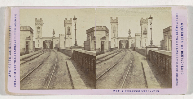 Schwarz-weißes stereoskopisches Bild einer Bahntrasse mit der Eisenbahnbrücke in Köln, Deutschland, das Schienen, Wände, Pfosten, Statuen, Himmel und Text zeigt.